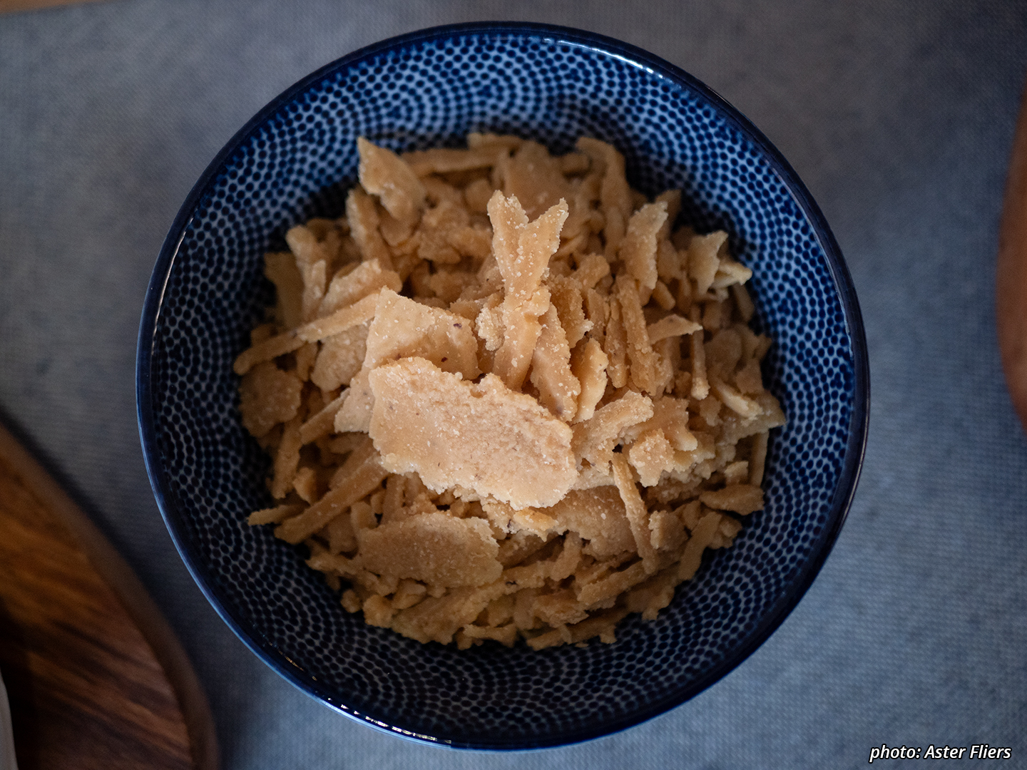 Picture of a ceramic bowl with cheese shards of ripened cashew and pine-nut with miso, aged and then dried until crumbly.